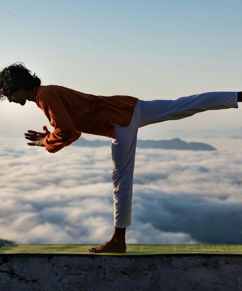 Silhouette of a man stretching against a sunrise, symbolizing harmony.